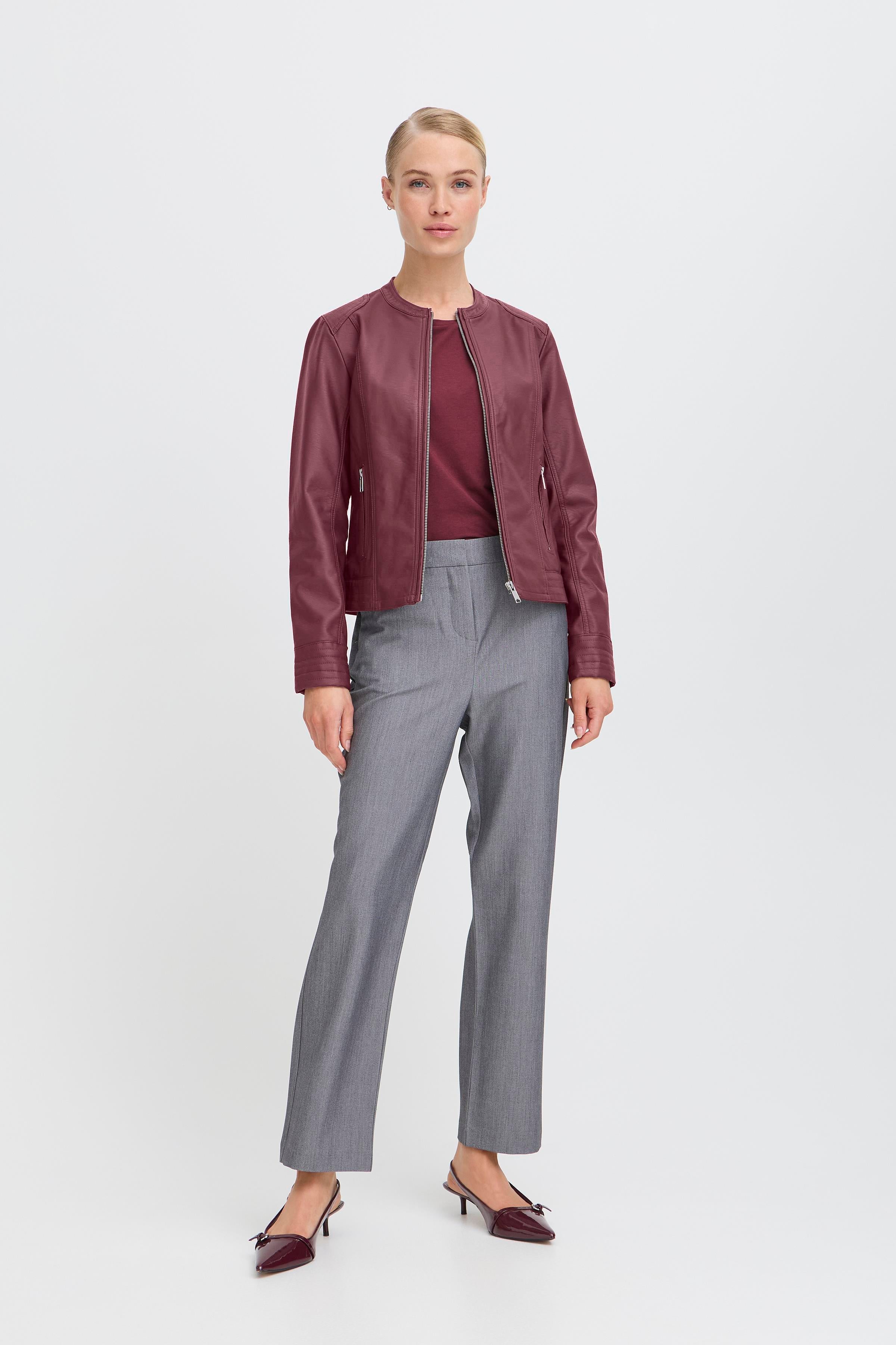 Woman wearing a maroon jacket and gray pants on a white background