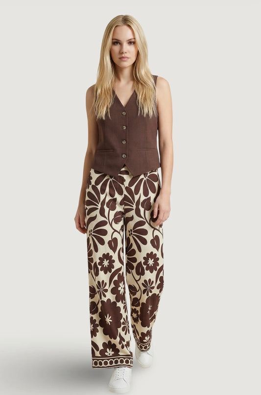 Woman wearing a brown sleeveless top and patterned pants on a white background